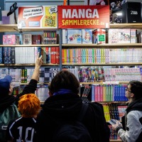 Besucher:innen an einem Messestand mit Mangaheften auf der Manga-Comic-Con 2024 Besucher:innen an einem Messestand mit Mangaheften auf der Manga-Comic-Con 2024