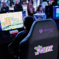 mehrere Personen spielen an Computern im Gamesroom der Manga-Comic-Con 2025, im Vordergrund ist ein Gamingchair von Secret Lab zu sehen mehrere Personen spielen an Computern im Gamesroom der Manga-Comic-Con 2025, im Vordergrund ist ein Gamingchair von Secret Lab zu sehen