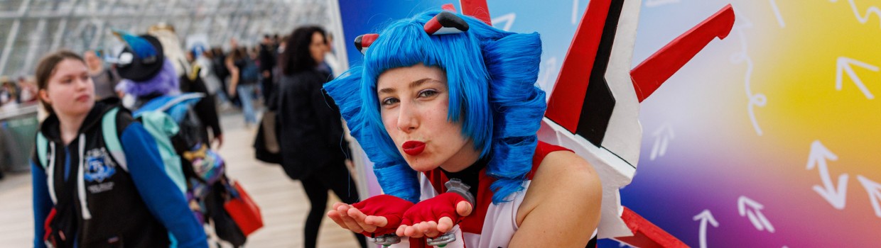 Das Maskottchen der Manga Comic Con Macoco macht einem Luftkuss vor einer bunten Leinwand auf der Manga Comic Con 2025 Das Maskottchen der Manga Comic Con Macoco macht einem Luftkuss vor einer bunten Leinwand auf der Manga Comic Con 2025