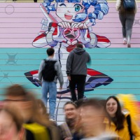 Besucher:innen gehen eine farbig gestaltete Treppe mit einem großen Manga-Motiv in der Leipziger Messe während der Manga Comic Con 2025 hinauf Besucher:innen gehen eine farbig gestaltete Treppe mit einem großen Manga-Motiv in der Leipziger Messe während der Manga Comic Con 2025 hinauf