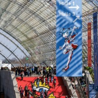 Menschenmengen auf roter Treppe unter einem Banner der Manga-Comic-Con 2025 mit Wegweisern und Manga-Figur in der Glashalle der Leipziger Messe Menschenmengen auf roter Treppe unter einem Banner der Manga-Comic-Con 2025 mit Wegweisern und Manga-Figur in der Glashalle der Leipziger Messe