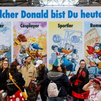 Besucher:innen vor vier großen Donald-Duck-Postern mit den Titeln 'Entdecker', 'Cosplayer', 'Sportler' und 'Romantiker' auf der Manga Comic Con 2025 Besucher:innen vor vier großen Donald-Duck-Postern mit den Titeln 'Entdecker', 'Cosplayer', 'Sportler' und 'Romantiker' auf der Manga Comic Con 2025