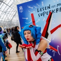 Das Maskottchen der Manga Comic Con Macoco macht einem Luftkuss vor einer bunten Leinwand auf der Manga Comic Con 2025 Das Maskottchen der Manga Comic Con Macoco macht einem Luftkuss vor einer bunten Leinwand auf der Manga Comic Con 2025