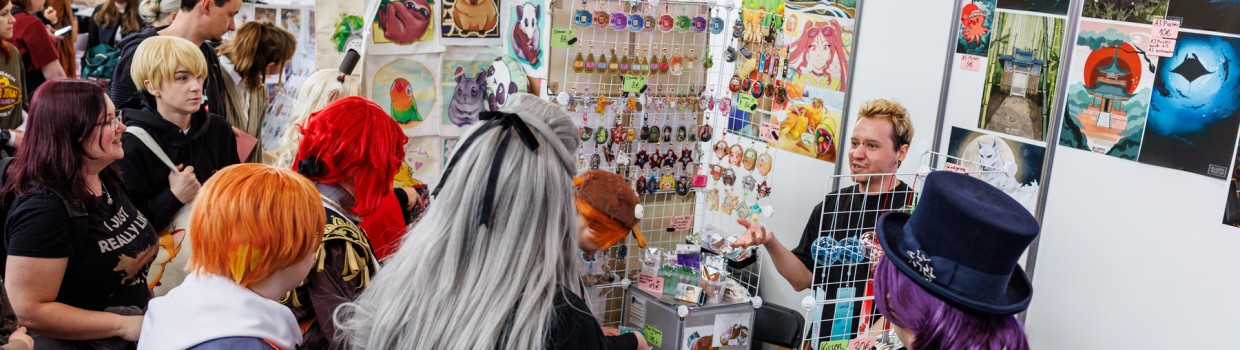 Künstlerstand mit Besucher:innen in der New Artist Alley auf der Manga-Comic-Con 2025 Künstlerstand mit Besucher:innen in der New Artist Alley auf der Manga-Comic-Con 2025