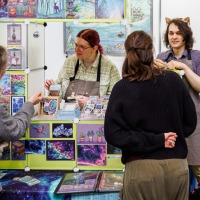 Künstlerstand mit Besucher:innen in der New Artist Alley auf der Manga-Comic-Con 2025 Künstlerstand mit Besucher:innen in der New Artist Alley auf der Manga-Comic-Con 2025