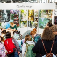 Künstlerstand mit Besucher:innen in der New Artist Alley auf der Manga-Comic-Con 2025 Künstlerstand mit Besucher:innen in der New Artist Alley auf der Manga-Comic-Con 2025